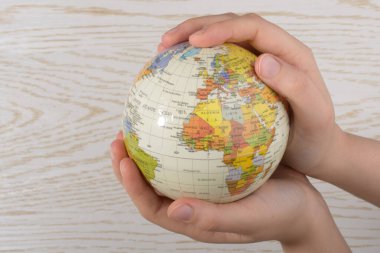 Hand holding a globe  with map on it clipart