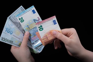 El ele tutuşan Amerikan doları banknotları siyah arka planda izole edilmiş.