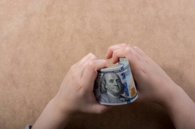 El ele tutuşan Amerikan doları banknotları ahşap arka planda izole edilmiş.