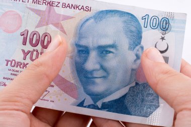 Beyaz arka plan üzerinde 100 Turksh Lirası banknotlar tutan el