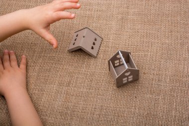 Çocuk keten bir tuvalde model bir evi tutuyor.