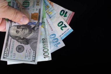 El ele tutuşan Amerikan doları banknotları siyah arka planda izole edilmiş.
