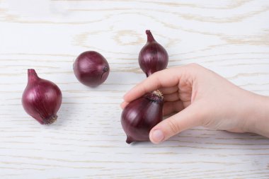 Tüm kırmızı soğan soğanları kahverengi ve ahşap arka planda