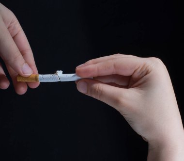 El siyah arka planda sigara kırıyor.