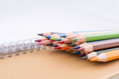 bir defter beyaz bir arka plan üzerinde renkli kalemler çeşitli renklerin yakınındaki