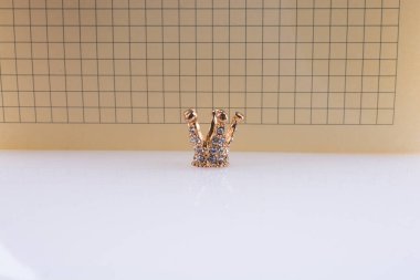 Beyaz zemin üzerinde bir not defteri ile taç