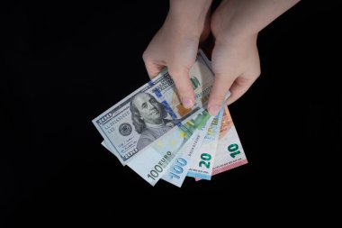 El ele tutuşan Amerikan doları banknotları siyah arka planda izole edilmiş.