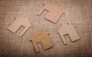 Tuvalin arka planında kağıttan yapılmış küçük bir ev şekli.