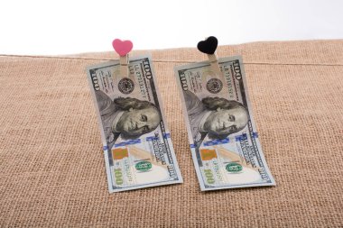 100 dolarlık banknotlar ve bir kalp klipsi.