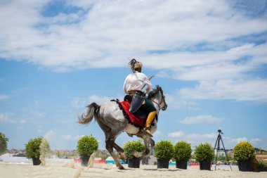 Osmanlı atlısı etnik kıyafetleriyle atına biniyor.
