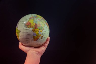 Üzerinde harita olan bir küreyi tutan el.