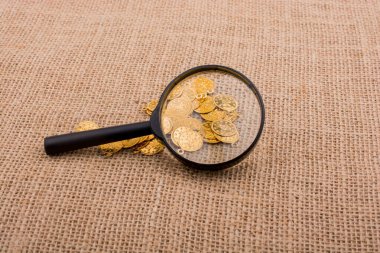 Büyüteç arkasında bir sürü sahte altın para var.