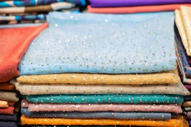 Bir pazarda çok renkli kumaş yığını.