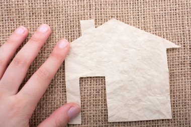 Tuvalin arka planında bir bez evi tutan el.