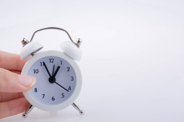 Bir çalar saat k beyaz arka plan üzerinde tutan çocuk