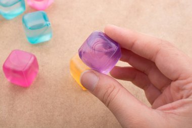 Sahte renkli Ice cube kahverengi arka planda tutan el