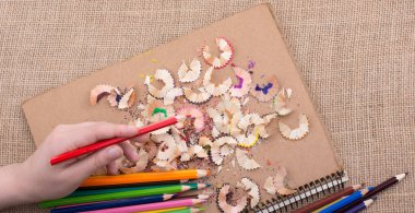 Kalem talaşı olan bir defterin üzerinde Renkli Kalem 'i tutarken