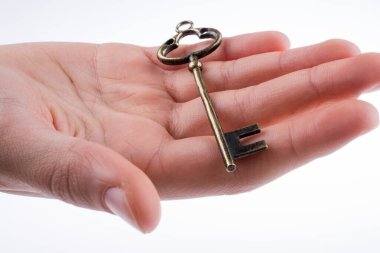 Beyaz arka planda eski moda metal bir anahtar tutan el.