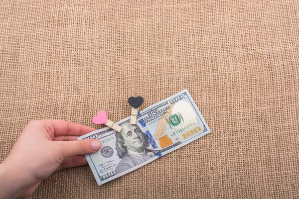 100 dolarlık banknotlar ve bir kalp klipsi.