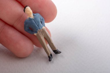 Elindeki minyatür insan figürü.
