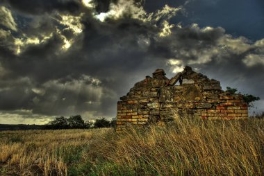 Harap bir kır evi ve arka planda kurşuni gökyüzü, bir yaz fırtınası geliyor..