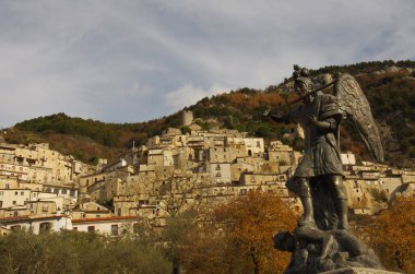 Pesche - Isernia - Molise - Önplanda San Michele heykeli ve ejderha ve arka planda taş evleri olan karakteristik köy.