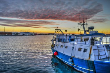 Termoli - Molise - Bir balıkçı teknesi limana yanaştı ve arka planda şafağın renkli gölgeleriyle gökyüzü