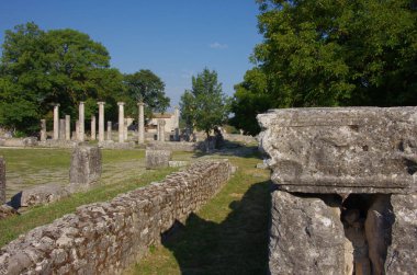 Altilia arkeolojik alanı: Ön planda megalitik taşlar ve Bazilika 'nın bir zamanlar nerede durduğunu gösteren sütunların arka planında. Sepino, Molise, İtalya