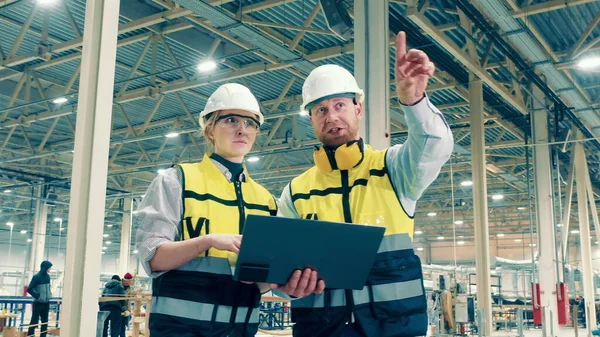 Two factory specialists are smiling while making plans. 4K