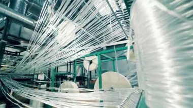 Strings of fiberglass are getting wound into rolls. 4K