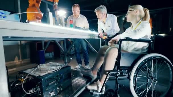 一位坐在轮椅上的妇女和她的同事正在研究4K机器人 — 图库视频影像