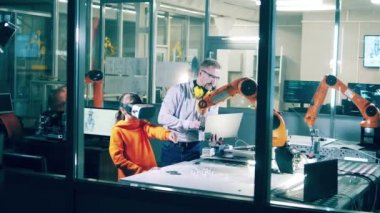 A tutor is helping a girl manage a VR-device to operate a robot. 4K