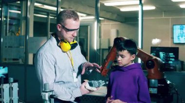 A tutor is showing a bionic hand to a boy. 4K