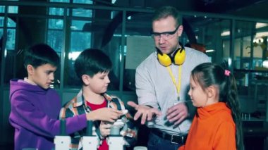 Male tutor is showing a bionic hand to a group of kids. 4K
