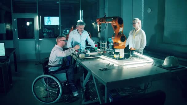 实验室里有一个坐在轮椅上的机器人工程师和他的同事4K — 图库视频影像