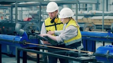 Two engineers are using a laptop while inspecting a fiberglass frame. 4K