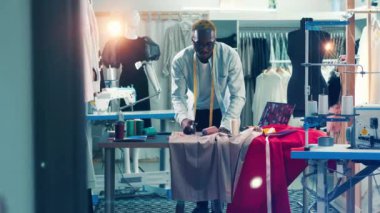 African dressmaker is cutting fabric in his studio. 4K