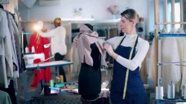 Female dressmaker is smiling next to the mannequin. 4K