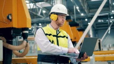 Fabrika mühendisi çalışırken bir dizüstü bilgisayar kullanıyor. 4K