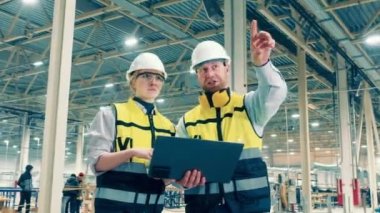 Two factory specialists are smiling while making plans. 4K