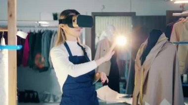 Female dressmaker is using a VR-device in her studio. 4K