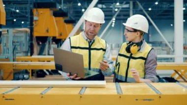 Two engineers are inspecting production of the fiberglass frames. 4K