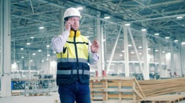 Factory facility with an engineer talking on the phone. 4K