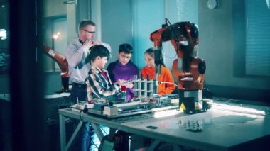 Robotic devices are being studied by children under supervision. 4K