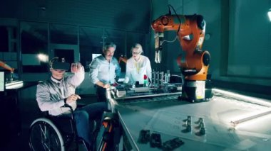A disabled engineer in VR-glasses is operating a robotic arm. 4K