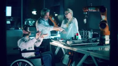 A disabled engineer in VR-glasses and his colleagues in the robotics lab. 4K