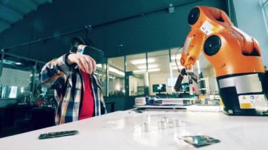 A boy in VR-glasses is operating a robotic arm. 4K