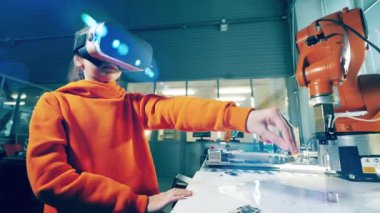 A girl is wearing VR-glasses with a robotic arm next to her. 4K
