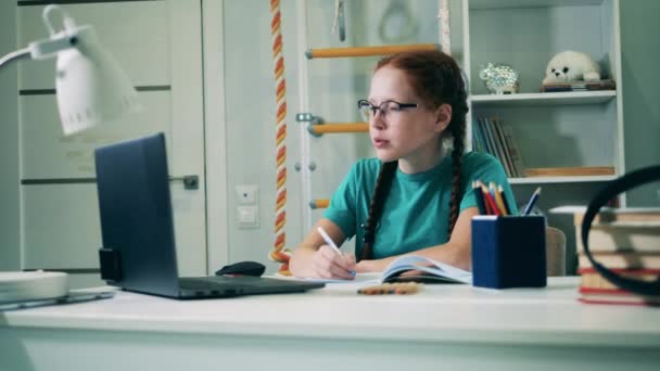 10代の少女はノートパソコンを使って家から遠隔で勉強している — ストック動画