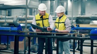 Two factory engineers are discussing a fiberglass bar. 4K